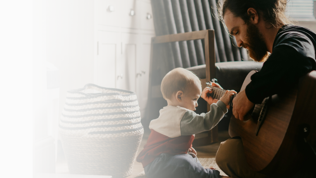 Advisory Council - Black and White image of Dad playing guitar with young baby