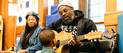 Man playing guitar and singing to child in Delaware
